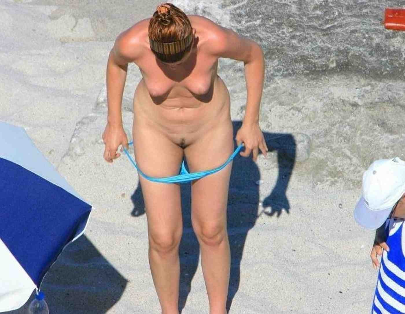 Une jeune femme chaude et excitée aux gros seins se déshabille sur la plage.
 #72242675
