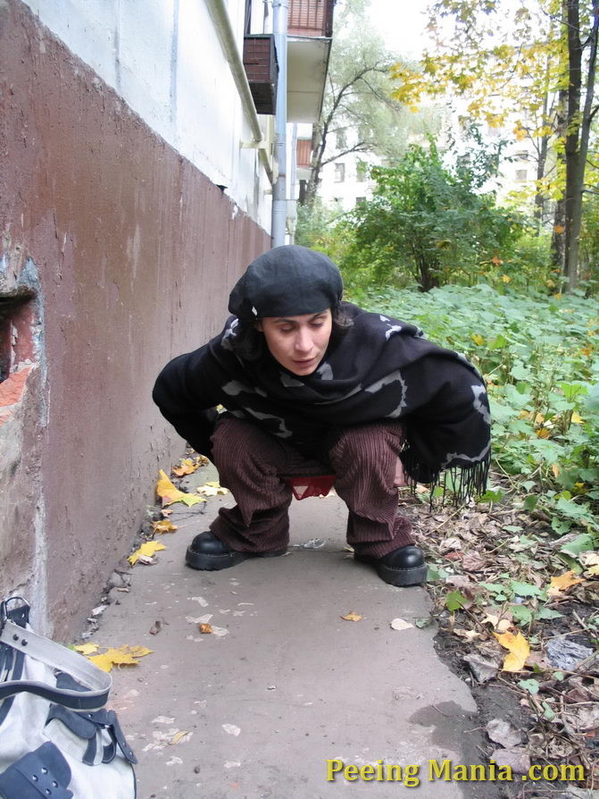 Stylishly dressed pretty woman does a leak behind a building in autumn #76571663