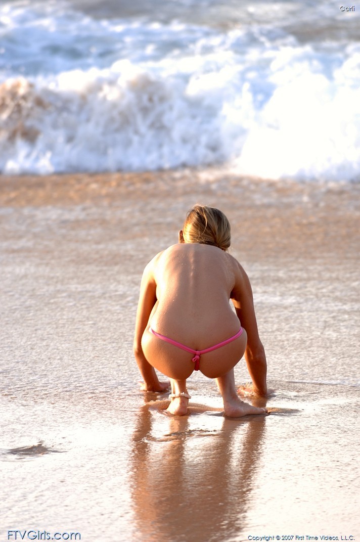 Bellezza giovane in perizoma che va in topless lungo la spiaggia
 #78628182