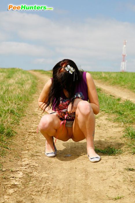 Chica emo orinando en medio de un camino rural
 #78691674