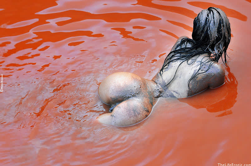 Bellezza nuda che si spalma il corpo nel fango rosso all'aperto in piscina rocciosa
 #72728143