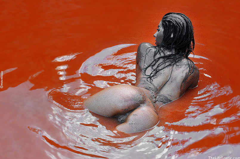 Bellezza nuda che si spalma il corpo nel fango rosso all'aperto in piscina rocciosa
 #72728147