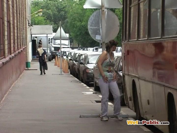 Chickie benetzt ihre weiße Hose hinter einem Bus, weil sie verzweifelt pinkeln muss
 #73247294