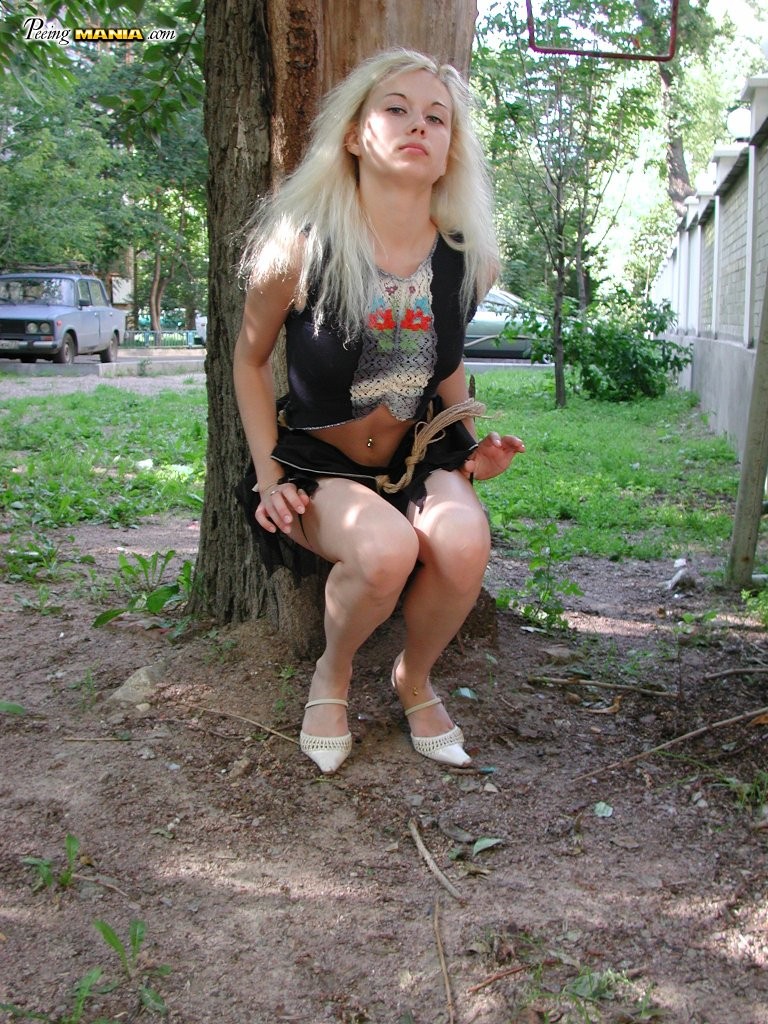 Une blonde en manque de pipi s'accroupit derrière un arbre pour se soulager dans le parc
 #76566444
