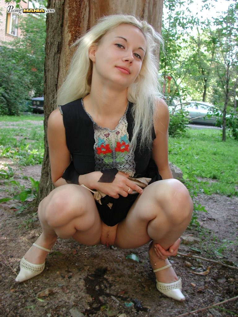 Une blonde en manque de pipi s'accroupit derrière un arbre pour se soulager dans le parc
 #76566469