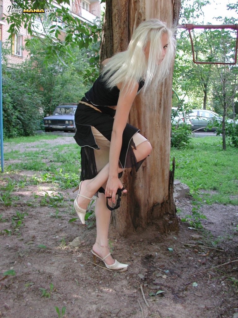 Une blonde en manque de pipi s'accroupit derrière un arbre pour se soulager dans le parc
 #76566496