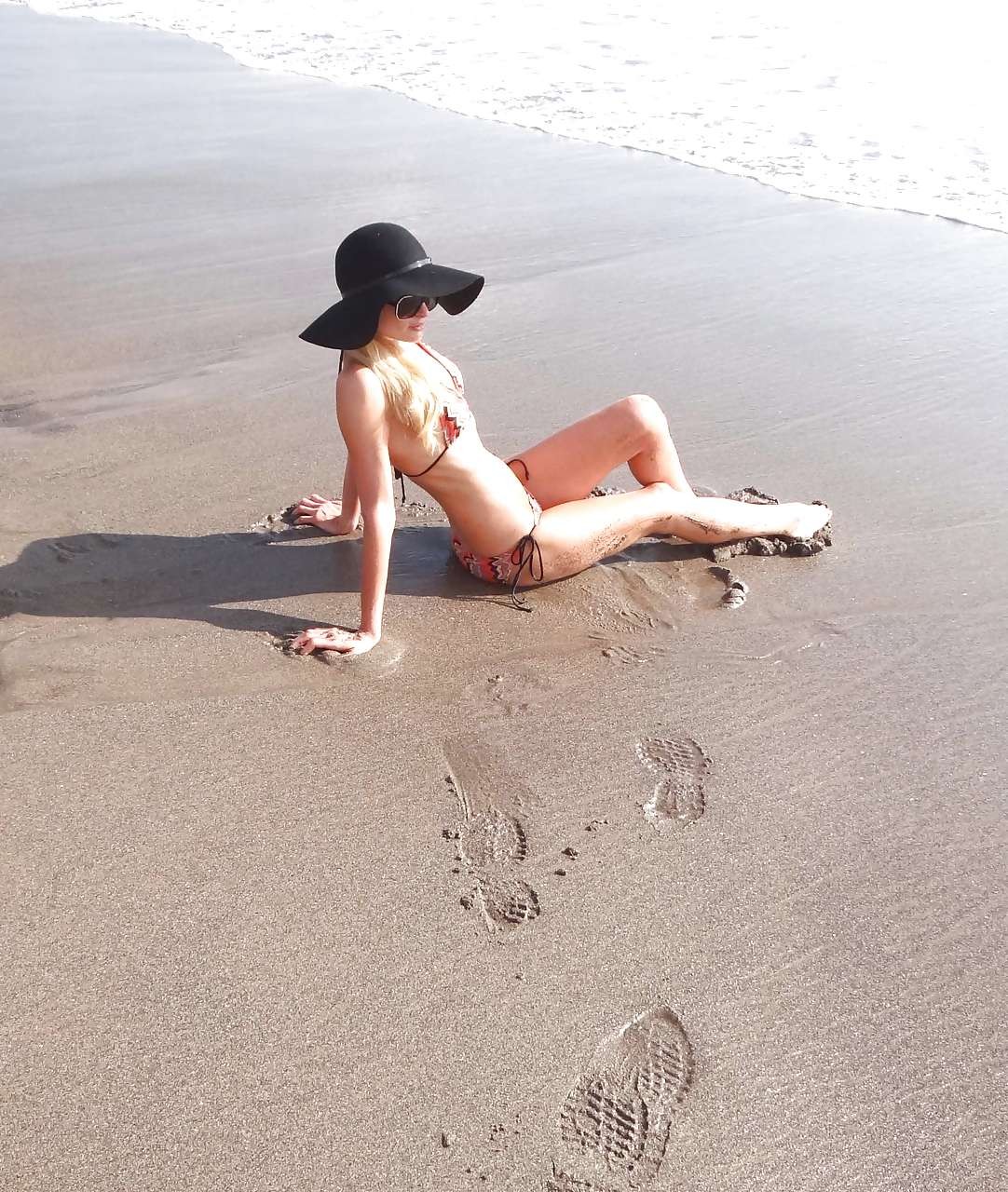 Paris Hilton en bikini moulant et chapeau noir sur une plage, photos paparazzi.
 #75282043