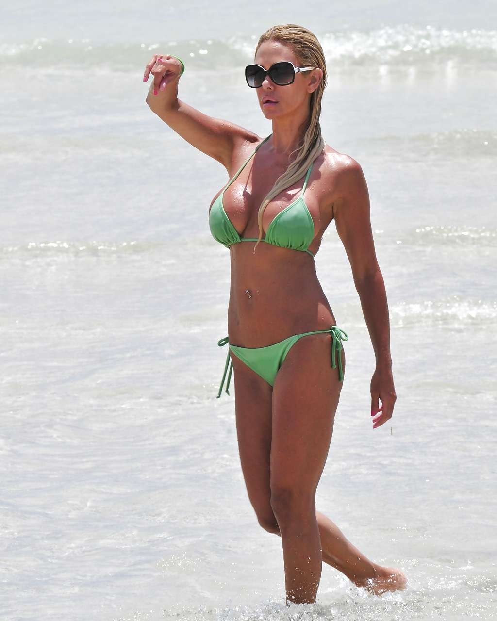 Shauna sand montrant ses superbes fesses dans un minuscule bikini vert sur la plage.
 #75296373