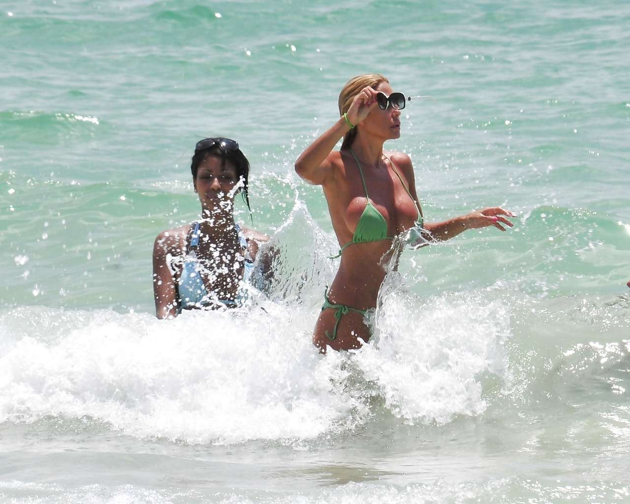 Shauna sand montrant ses superbes fesses dans un minuscule bikini vert sur la plage.
 #75296403