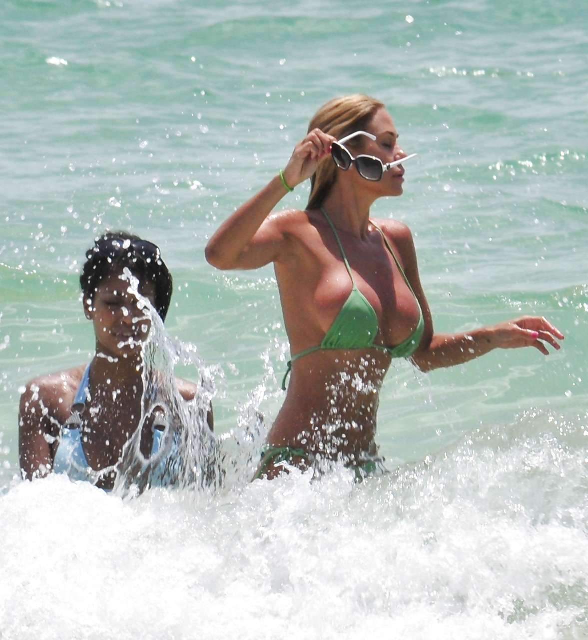 Shauna sand montrant ses superbes fesses dans un minuscule bikini vert sur la plage.
 #75296410