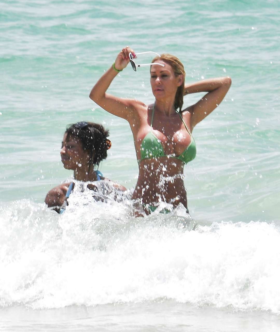 Shauna sand montrant ses superbes fesses dans un minuscule bikini vert sur la plage.
 #75296416