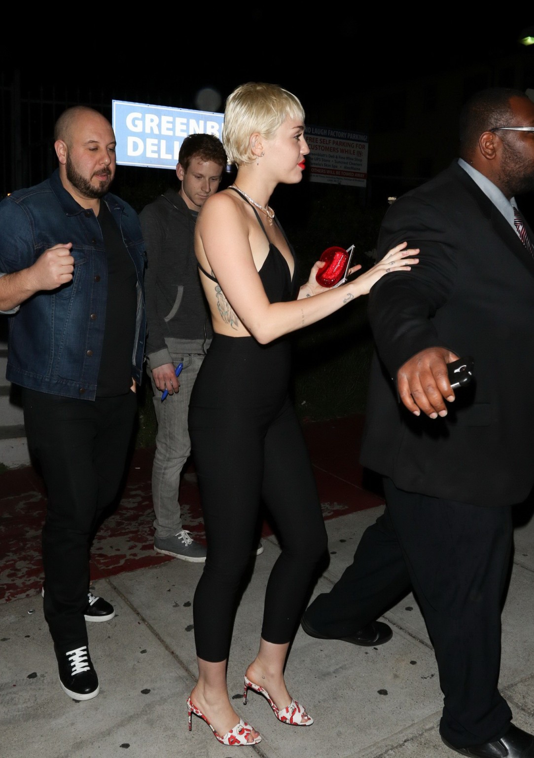 Miley Cyrus braless wearing tight black bareback jumpsuit night out in Los Angel #75169389