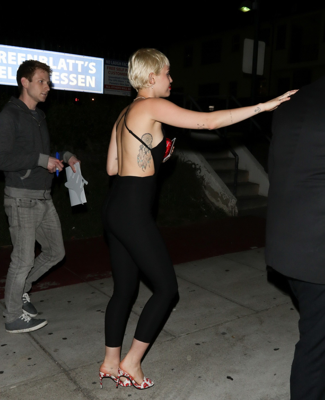 Miley Cyrus braless wearing tight black bareback jumpsuit night out in Los Angel #75169391