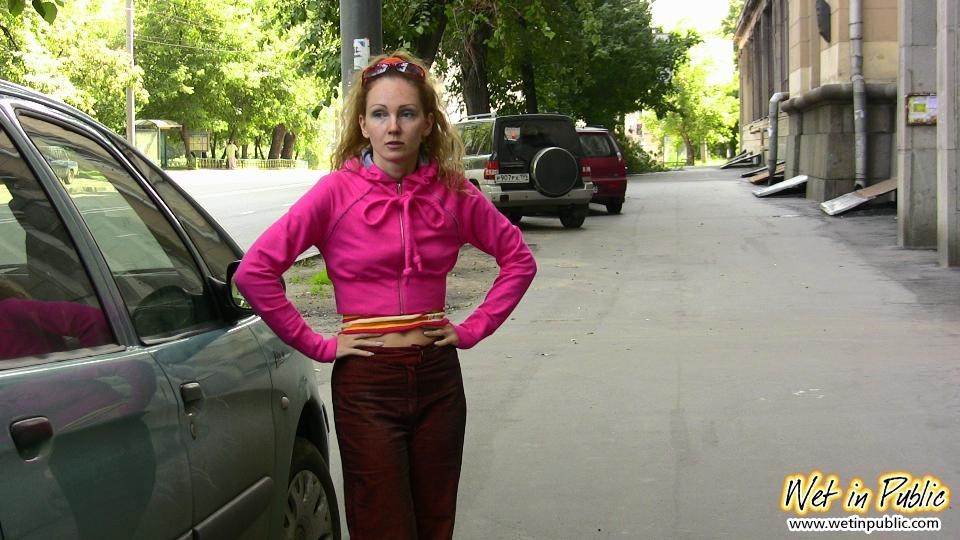 Nena desagradable moja sus pantalones carmesí detrás de un coche en el patio
 #73244396