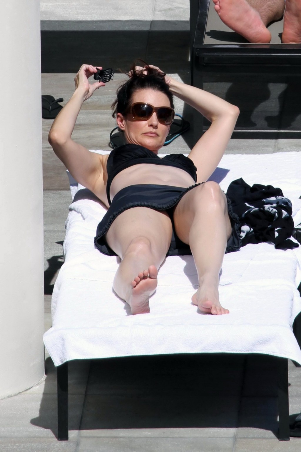 Kristin davis en mini jupe et haut de bikini noir bronzant au bord d'une piscine à hawaii
 #75328940
