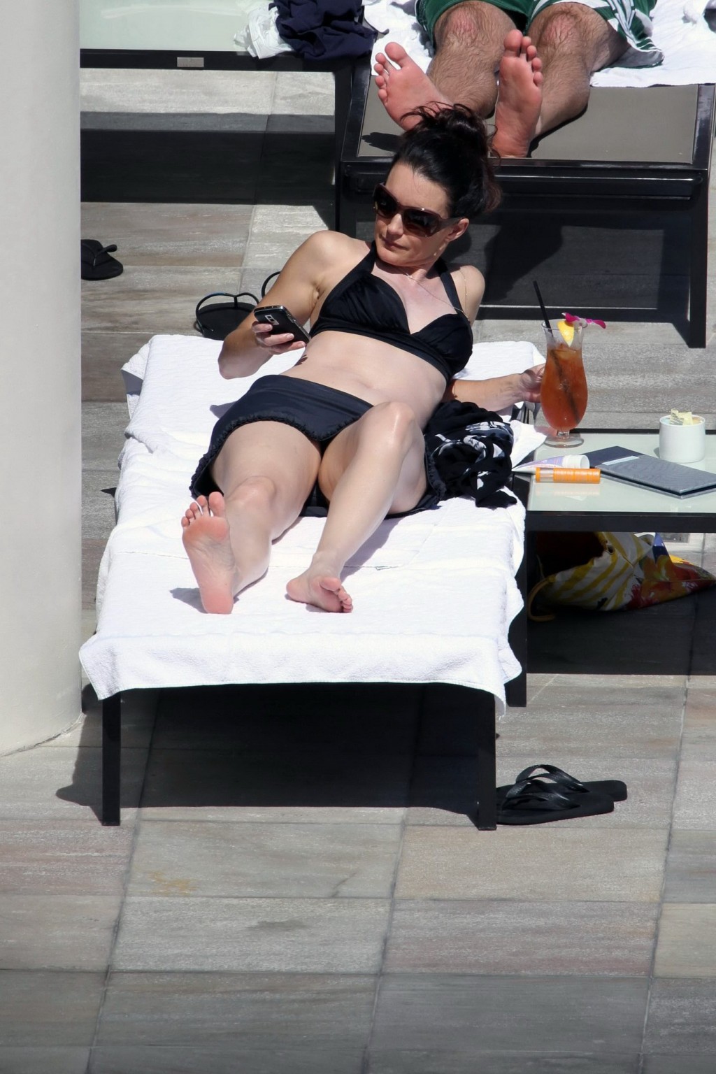Kristin davis en mini jupe et haut de bikini noir bronzant au bord d'une piscine à hawaii
 #75328996