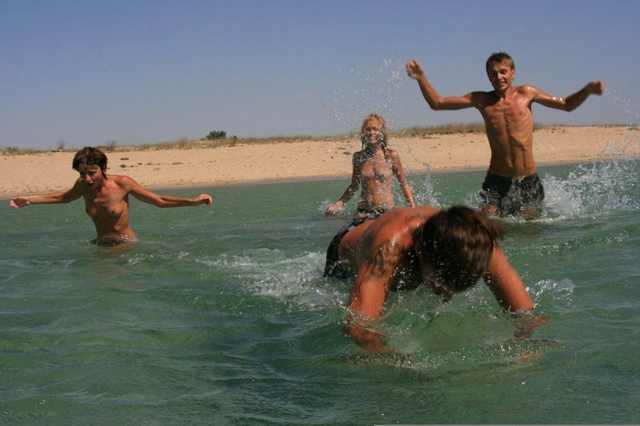 Questi due giovani nudisti giocano a frisbee nell'acqua
 #72255218