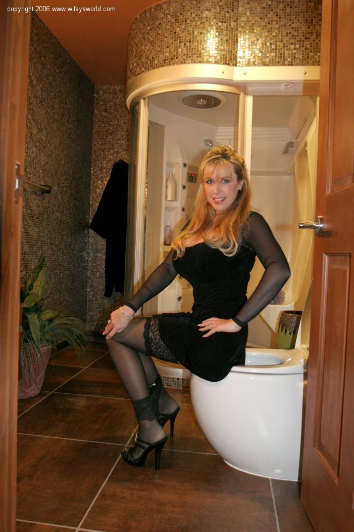Sexy blond wife in black lingerie undressing in her bathroom