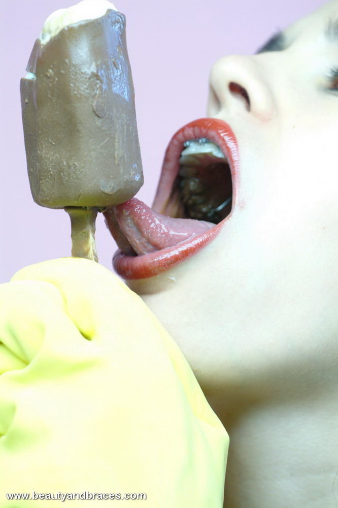 Jeune brune avec un appareil dentaire qui se salit avec une sucette glacée.
 #73259324