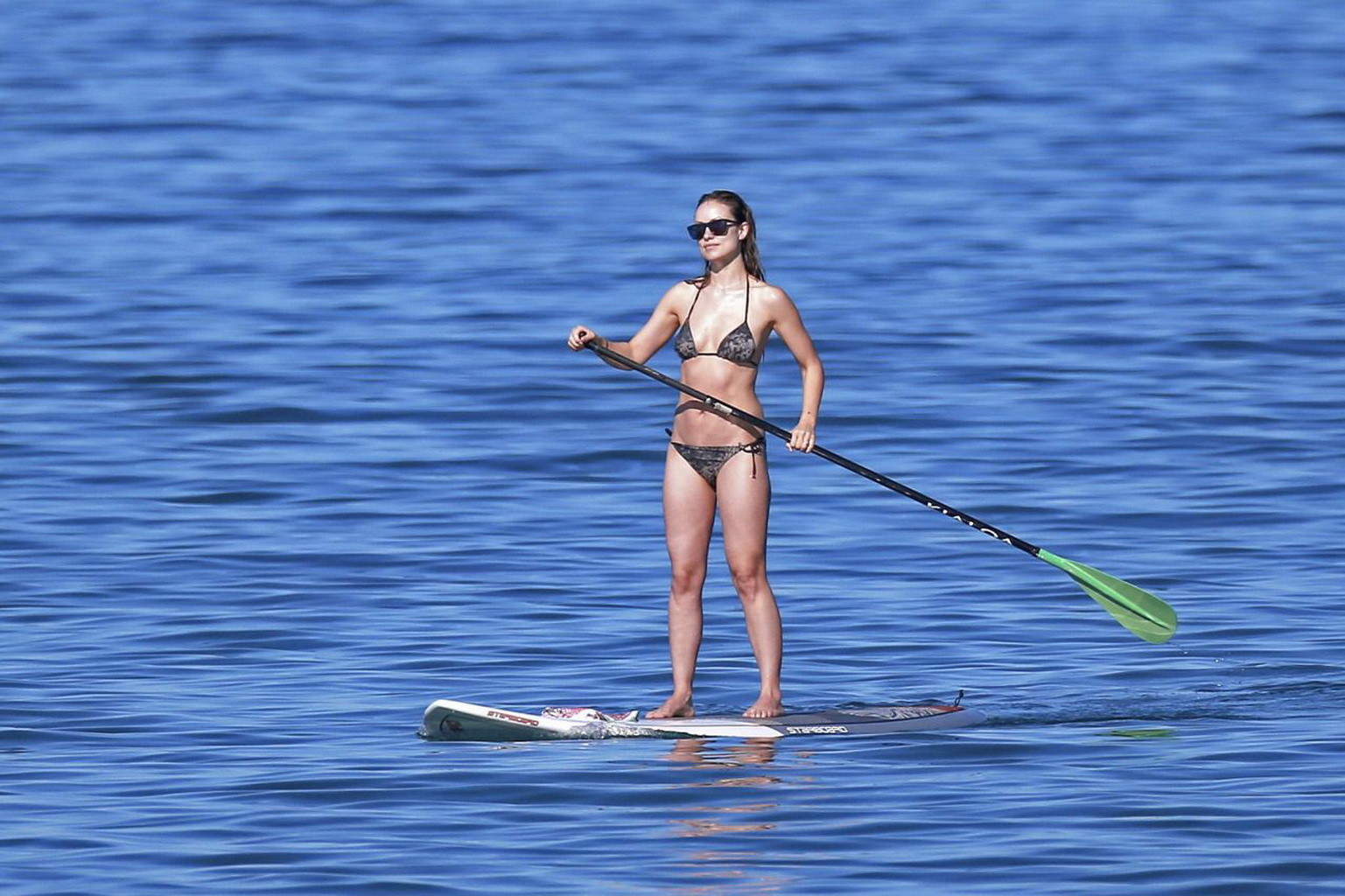 Olivia wilde montrant ses fesses dans un minuscule bikini monochrome à imprimé floral tout en faisant du paddle.
 #75179043