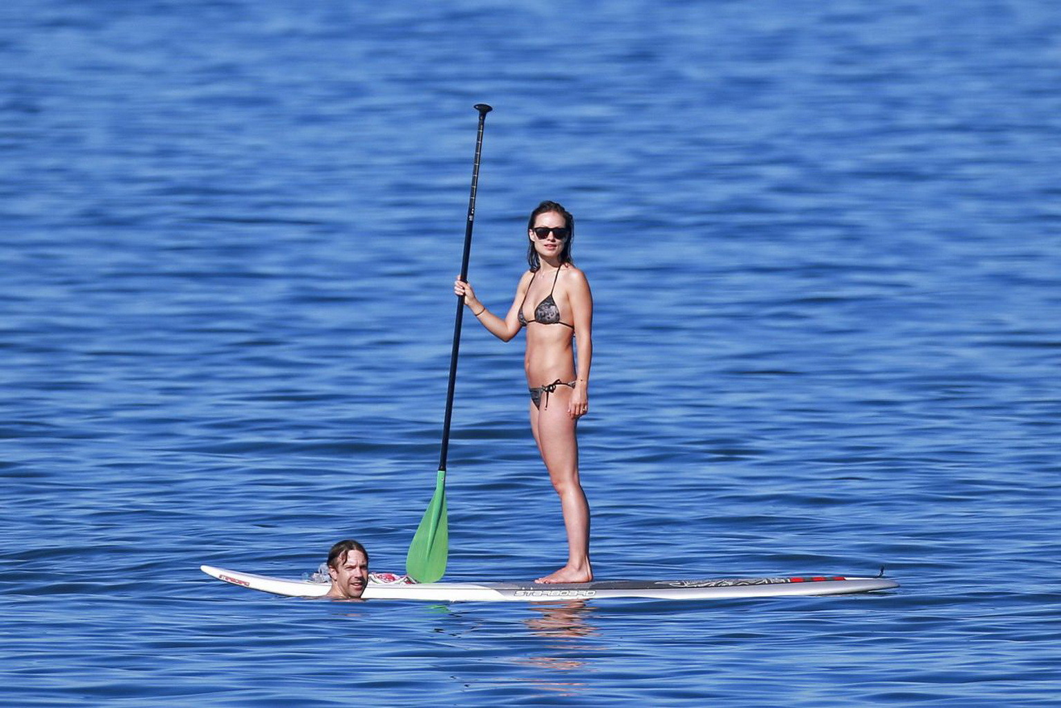 Olivia wilde montrant ses fesses dans un minuscule bikini monochrome à imprimé floral tout en faisant du paddle.
 #75179046