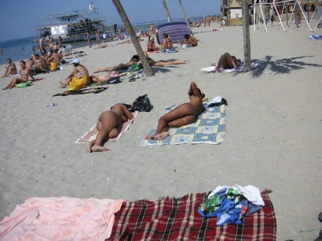 Giovani nudisti si spogliano e riscaldano una spiaggia pubblica
 #72255927