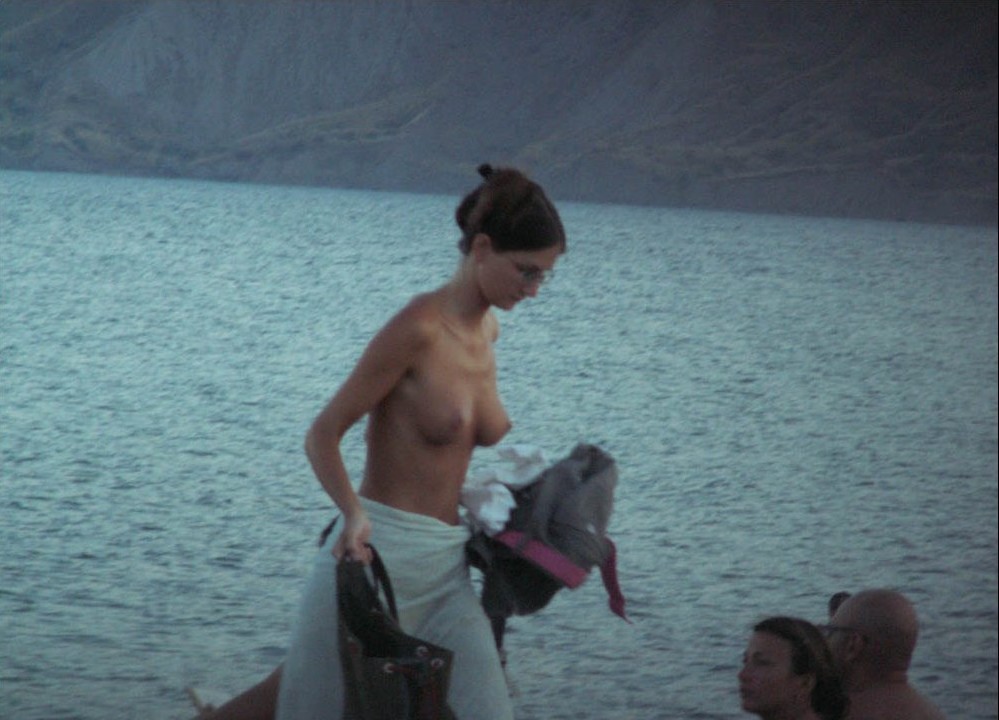 Guarda una ragazza nuda in spiaggia che abbronza il suo corpo caldo
 #72252044