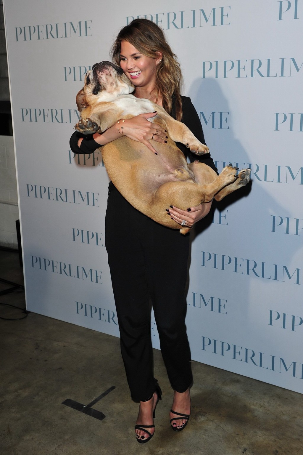Chrissy Teigen braless  cleavy petting two ugly bulldogs at the new Piperlime co #75184366