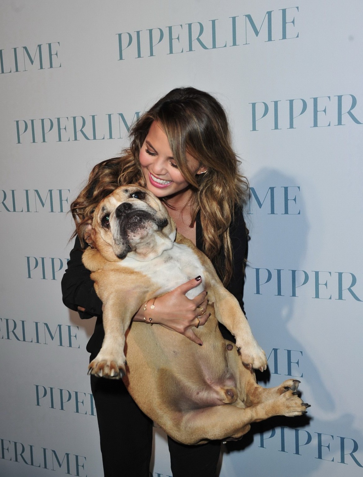 Chrissy Teigen braless  cleavy petting two ugly bulldogs at the new Piperlime co #75184374
