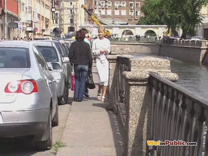 Une blonde mignonne trempe son jean blanc avec de la pisse en plein milieu d'une rue animée.
 #78595068