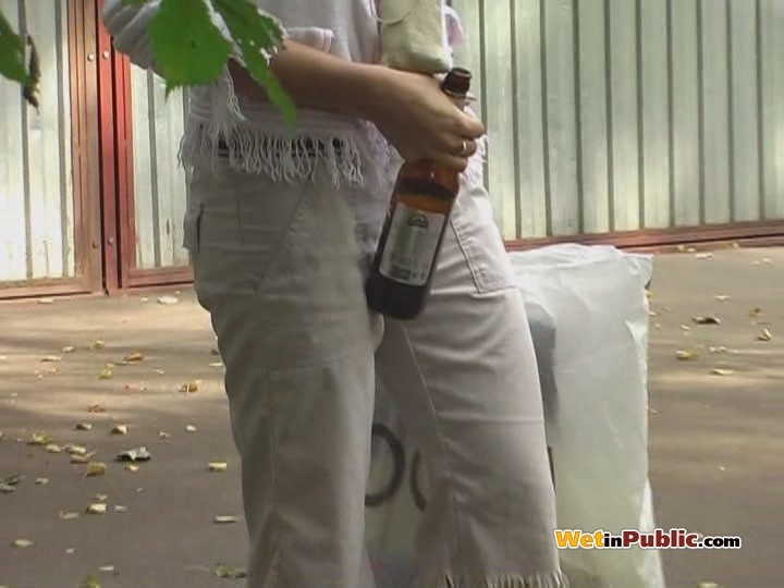 ブロンドの女性がビールを飲みながら、白いズボンに小便をする。
 #78590944