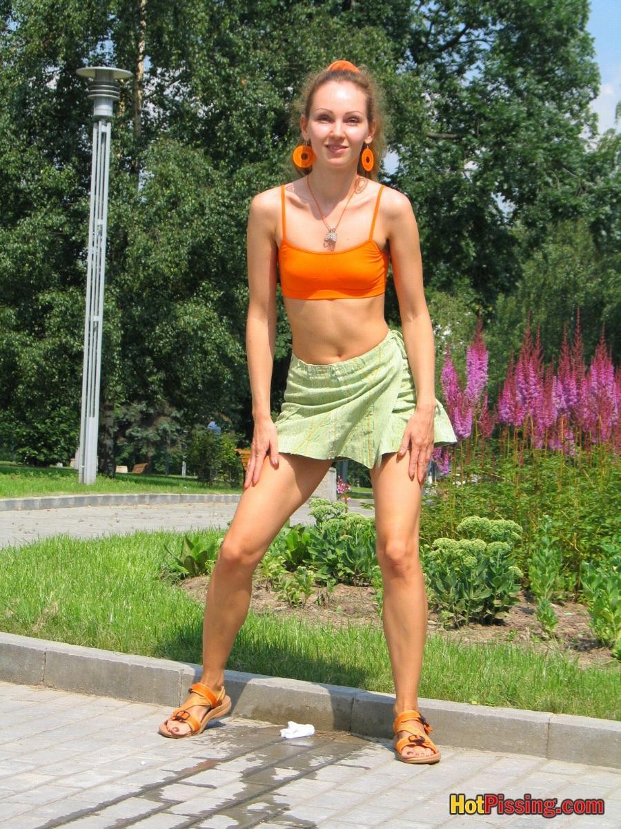 Babe in green and orange sits down on a border and does a piss coolly #76525631