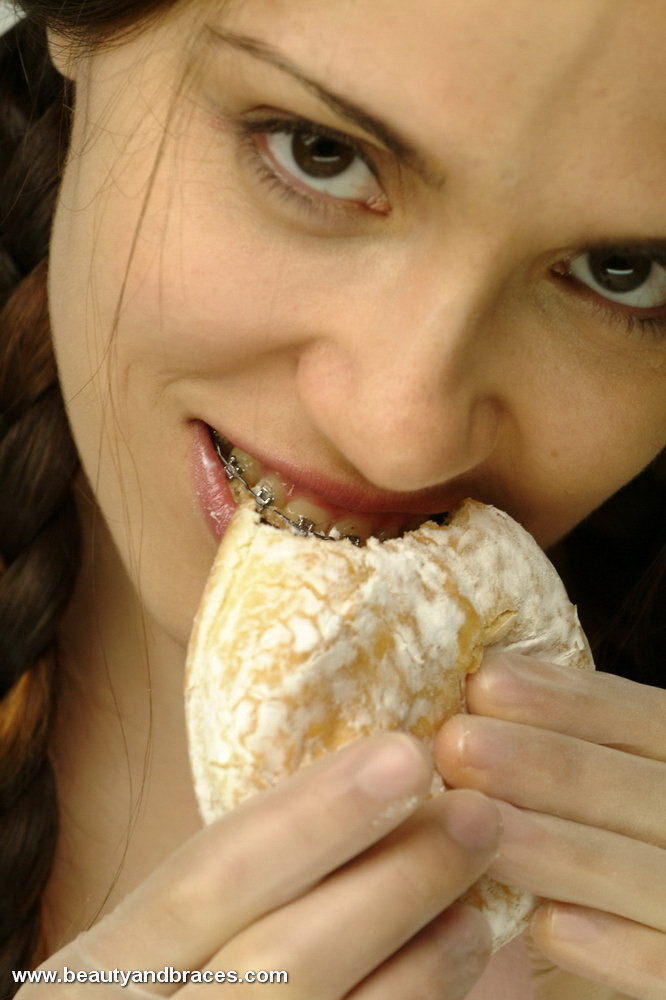 Une jeune avec une queue de cochon et un appareil dentaire enfonce un beignet dans sa bouche sexy.
 #74900331