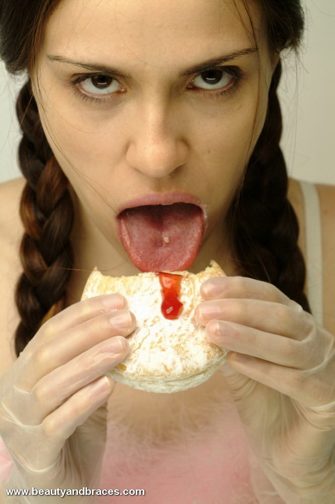 Une jeune avec une queue de cochon et un appareil dentaire enfonce un beignet dans sa bouche sexy.
 #74900337