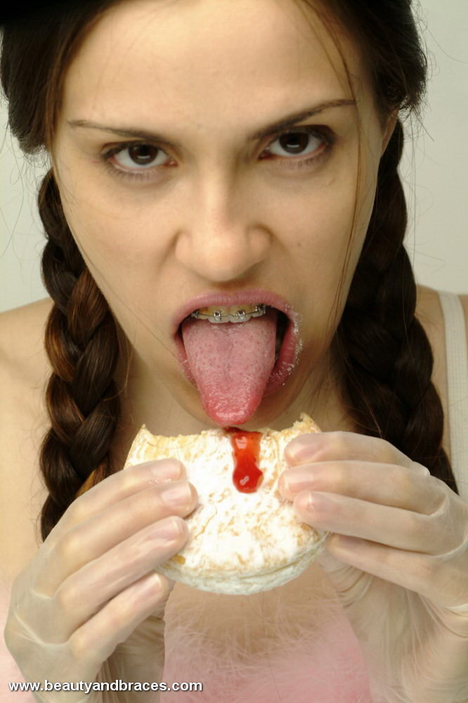 Une jeune avec une queue de cochon et un appareil dentaire enfonce un beignet dans sa bouche sexy.
 #74900341
