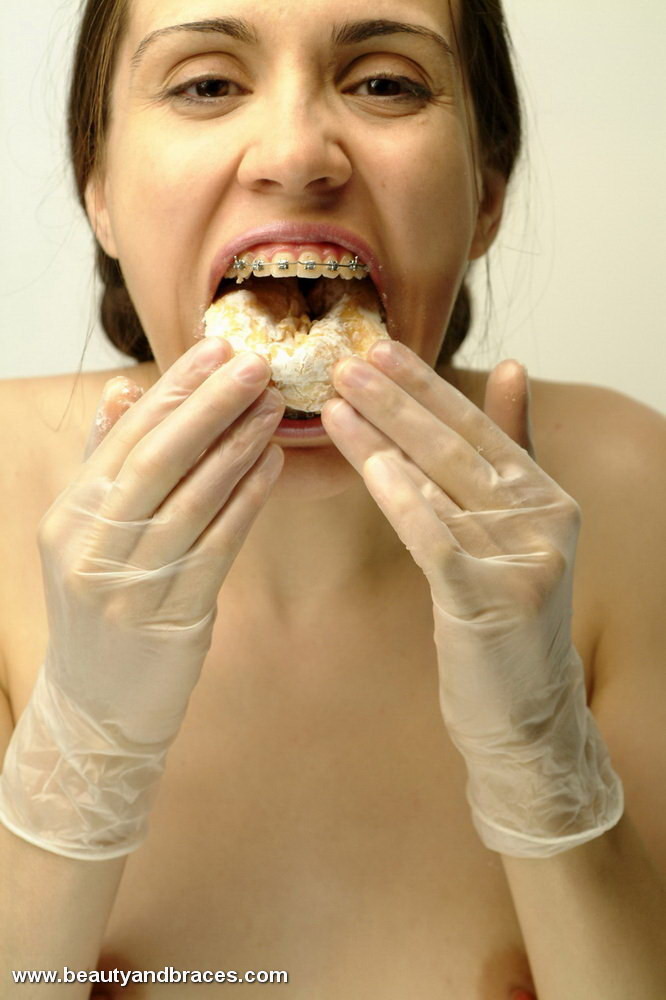 Une jeune avec une queue de cochon et un appareil dentaire enfonce un beignet dans sa bouche sexy.
 #74900369