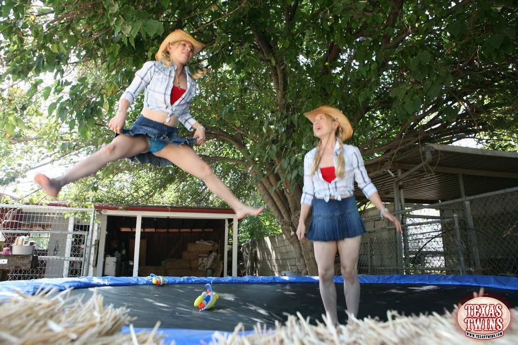 Deux sœurs jumelles jeunes jouent avec des pistolets à eau et sautent sur un trampoline.
 #78657244