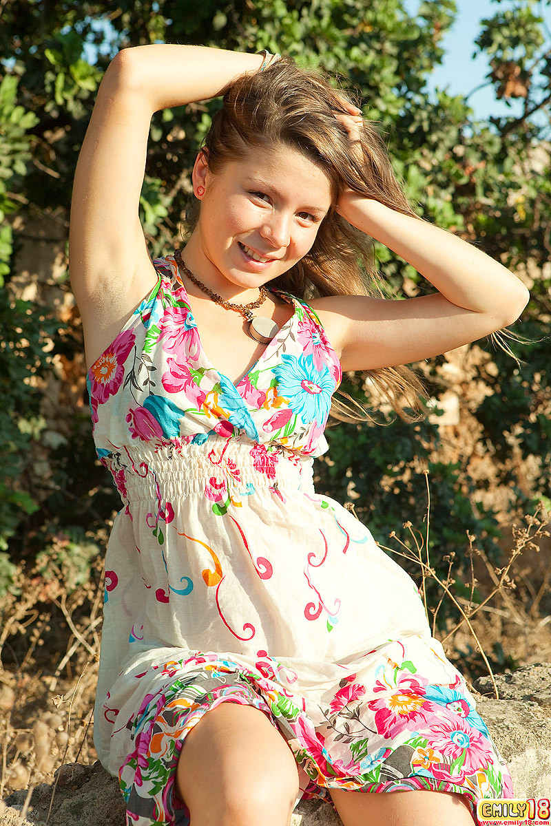 Emily 18 est assise sur un rocher à l'extérieur dans sa jolie robe à fleurs et elle sourit à la foule.
 #67216875