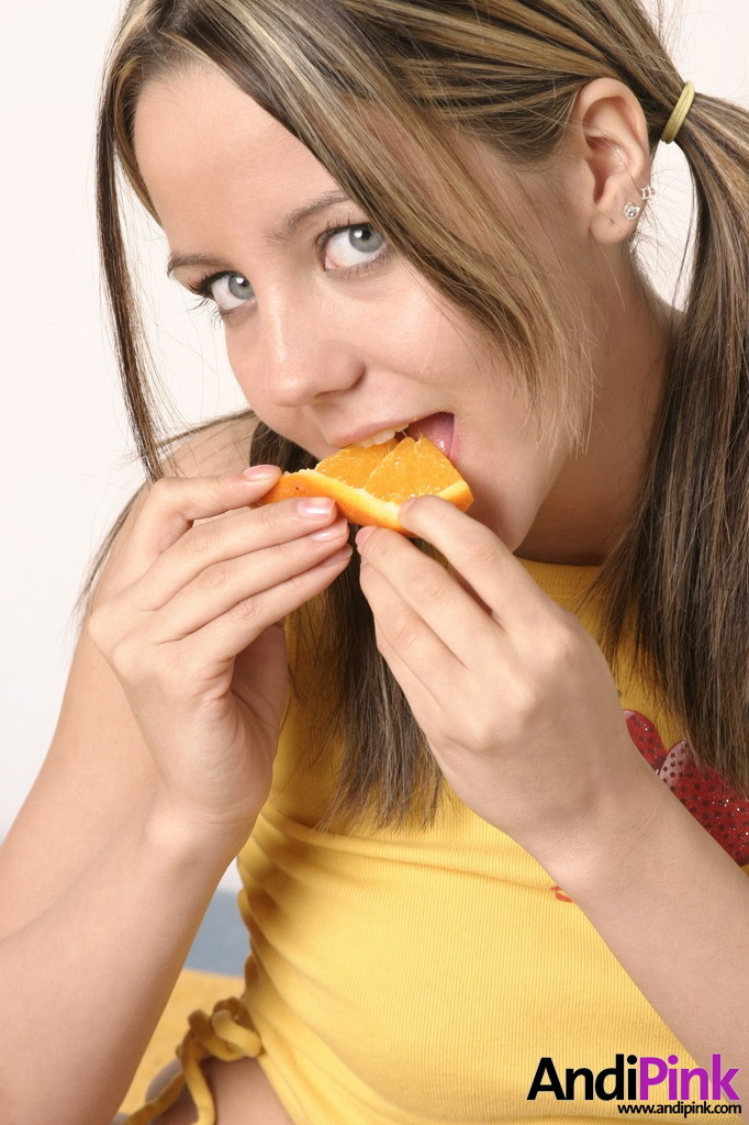 Linda chica joven con coletas comer naranja
 #67208715