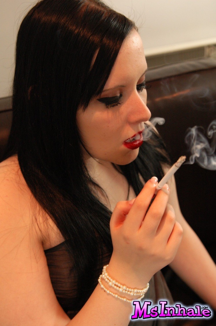 Una chica traviesa se saca las tetas del vestido mientras fuma un cigarrillo largo
 #70266663
