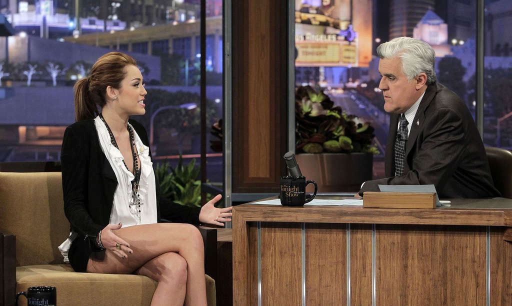 Miley Cyrusがテレビ番組で黒のミニスカートを履いて脚を見せている。
 #75354784
