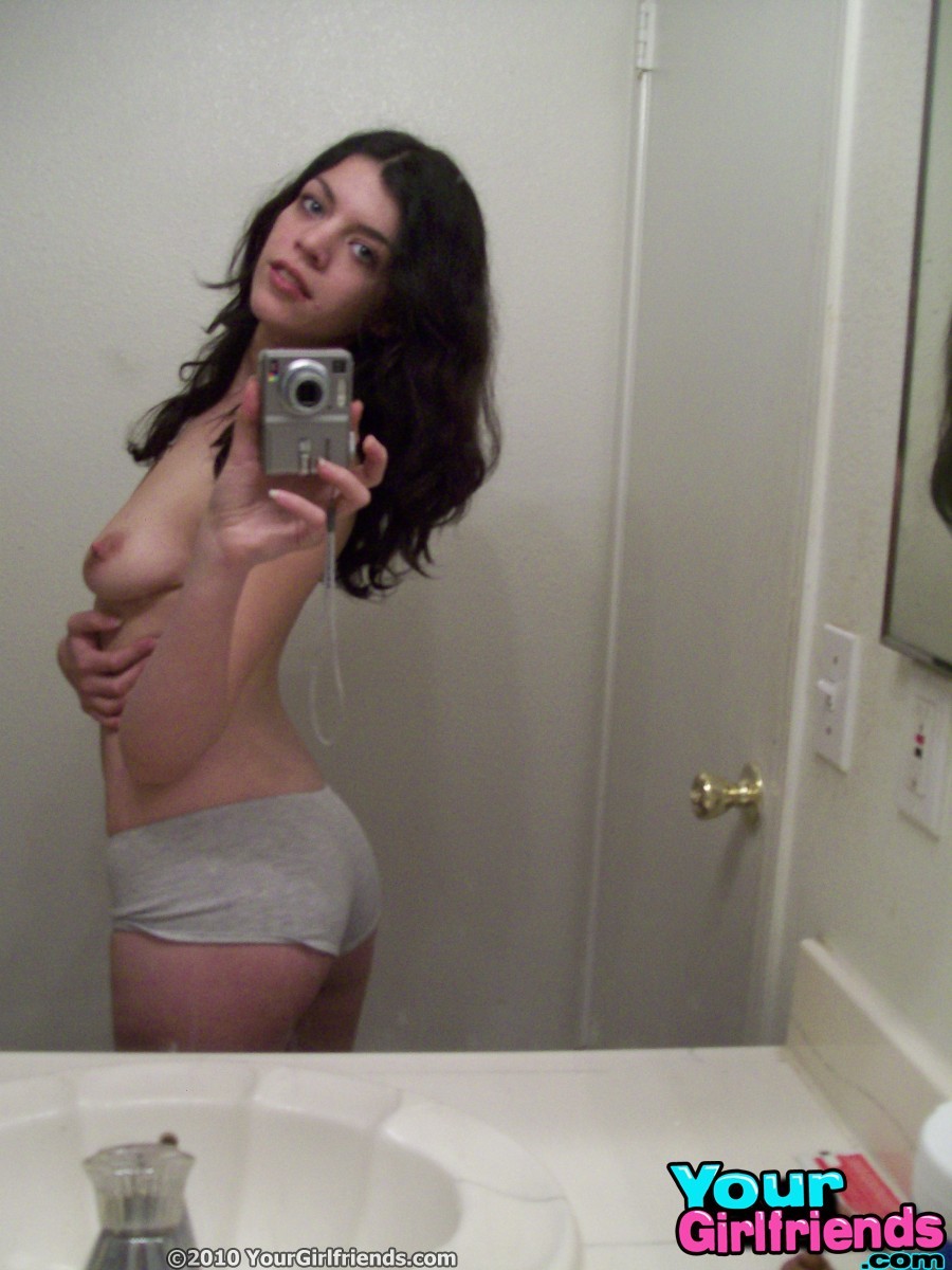 Une jeune dans la salle de bain joue avec son corps tout en prenant des photos dans le miroir.
 #67175301