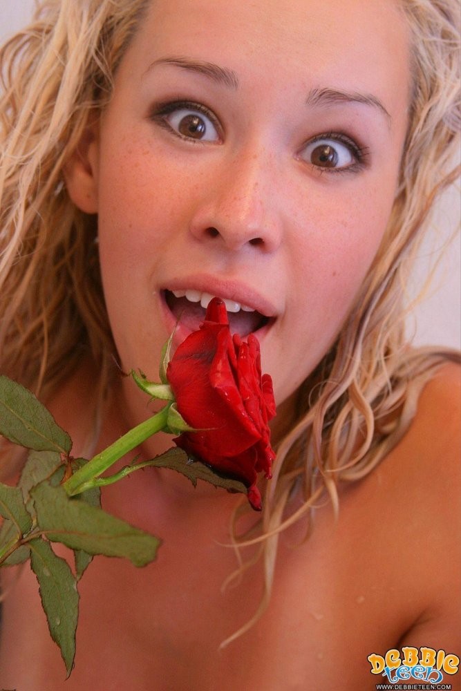 赤いバラを持って裸でポーズをとる若いティーンのデビー
 #76450453