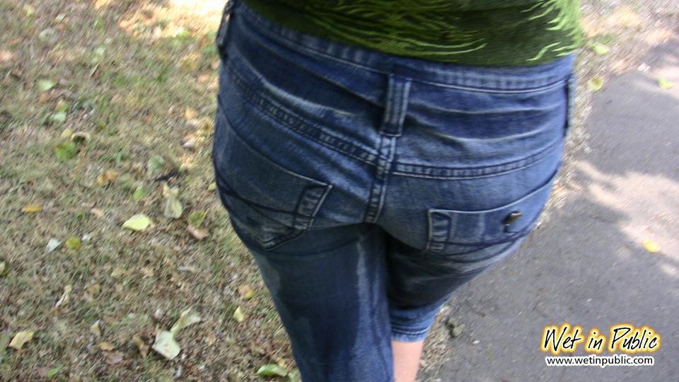 Chica atractiva moja sus pantalones vaqueros y se cambia detrás de los arbustos
 #73239210