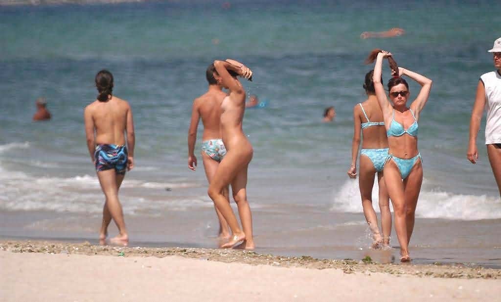 Una joven nudista de pelo oscuro se broncea por completo en la playa
 #72253597