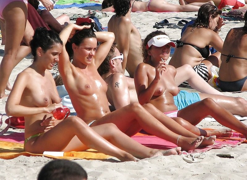 Nackte Freunde spielen an einem öffentlichen Strand
 #72244034
