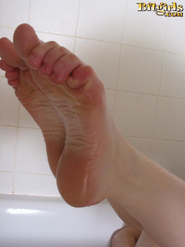 Brünettes Mädchen wird ganz nass in der Badewanne und spielt mit ihren Füßen
 #60254404