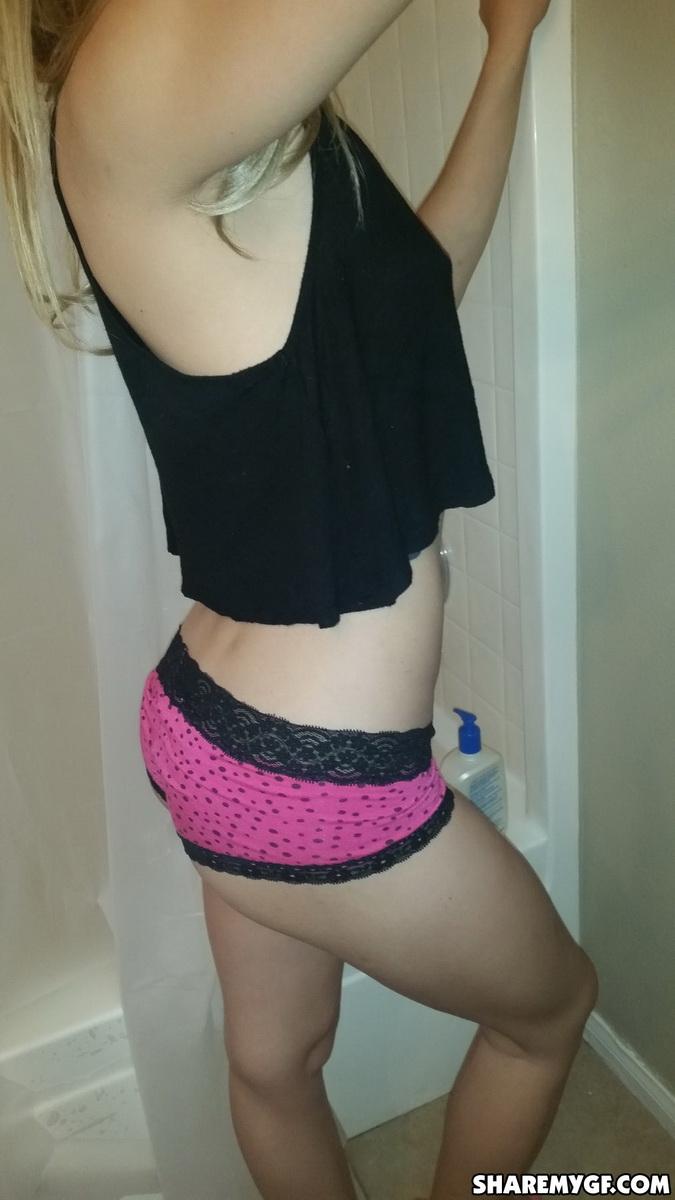 Une petite amie maigre se prend en photo dans sa jolie culotte rose devant le miroir de la salle de bain.
 #60789474