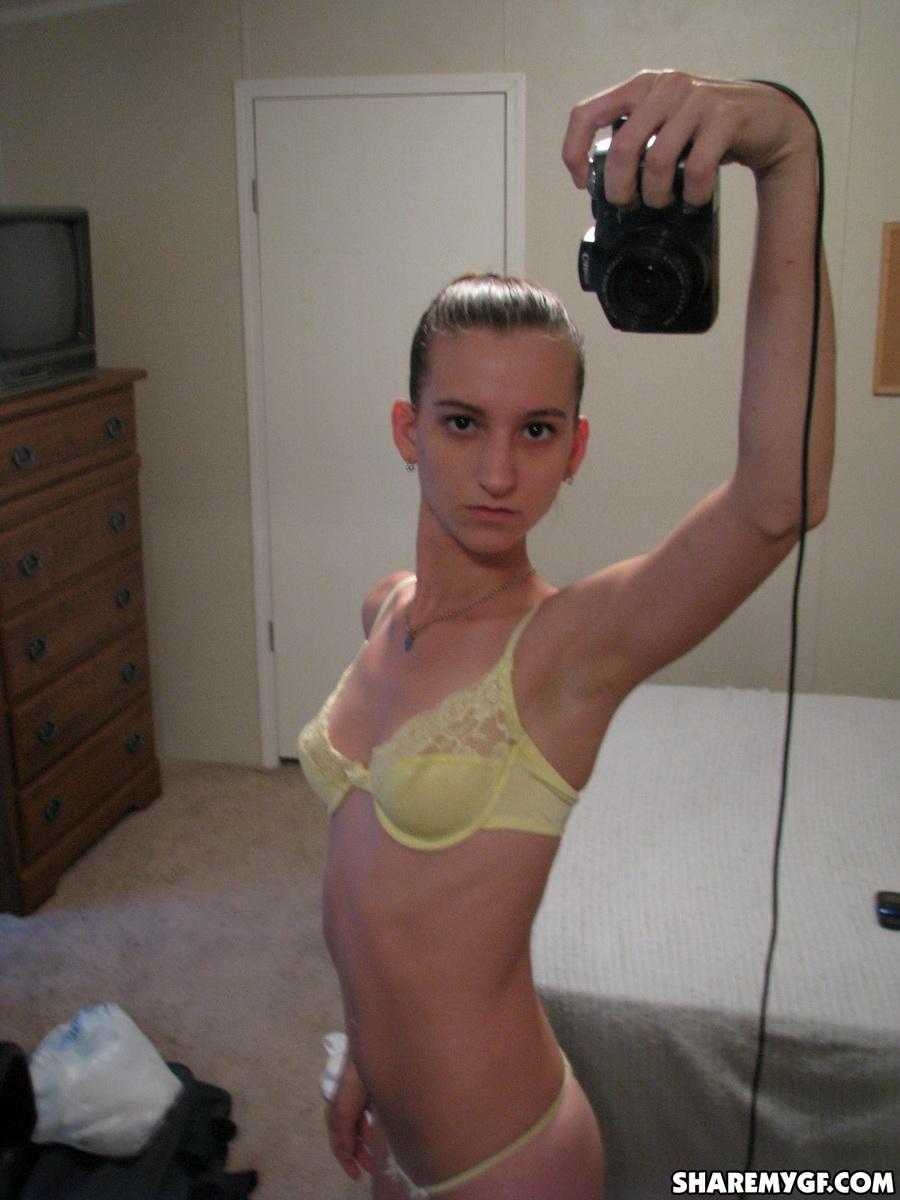 Une petite amie maigre prend des photos de ses seins dans le miroir dans un soutien-gorge en dentelle jaune.
 #60790245