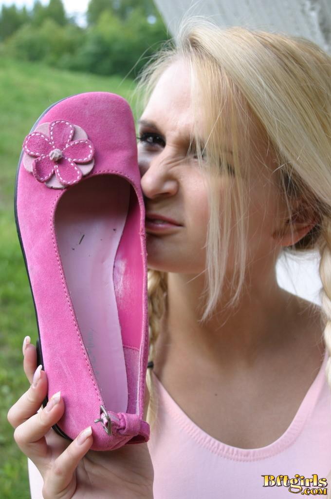 Joven rubia con coletas se quita los zapatos rosas y juega con sus pies
 #60256862